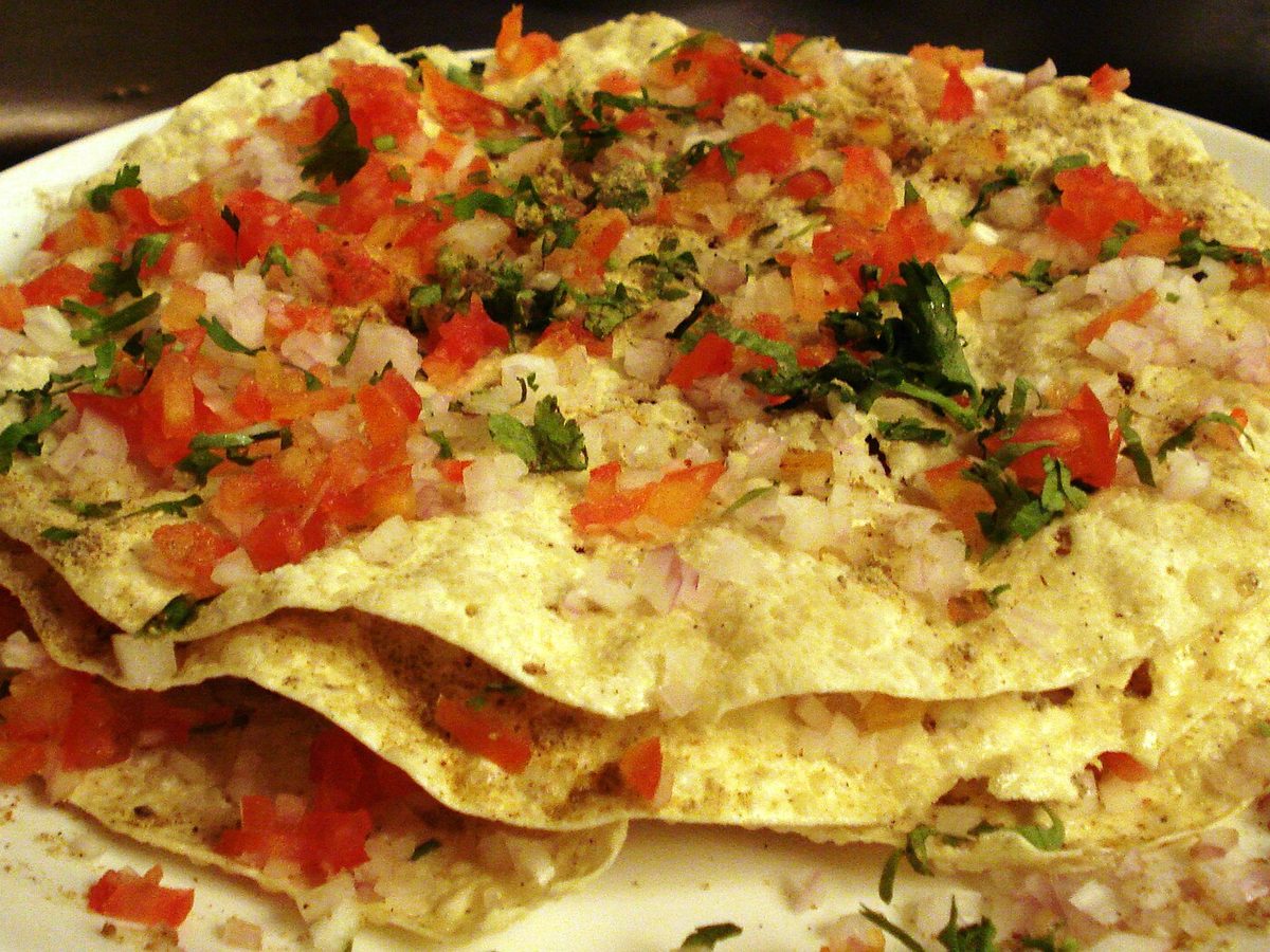 Masala papad topped with chopped onion, tomato and coriander