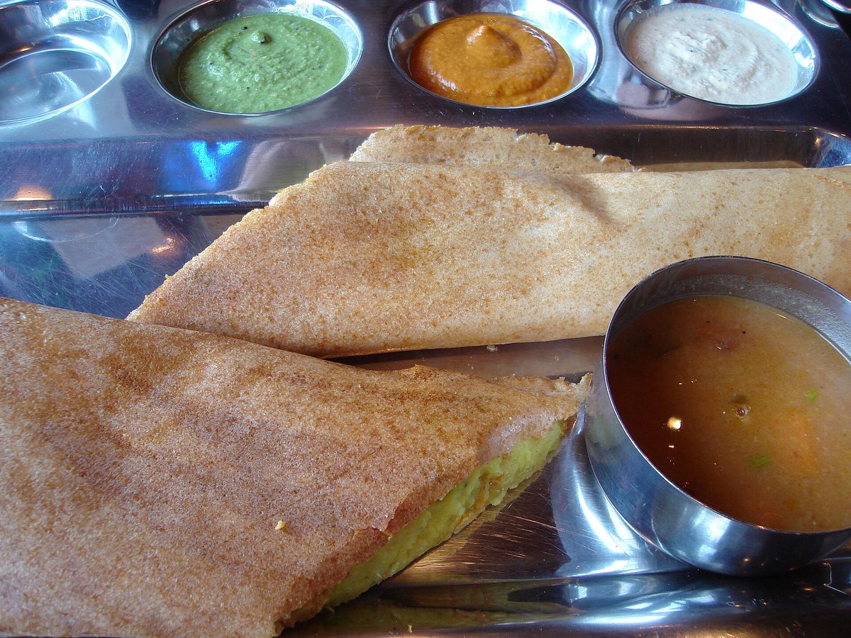 Mysore masala dosa on a steel plate with sambar and three chutneys